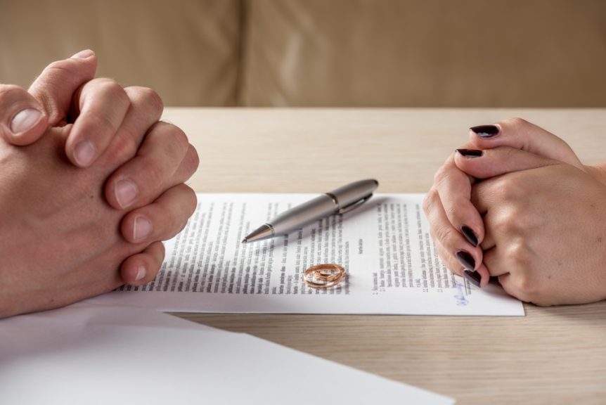 Hands of wife and husband signing divorce