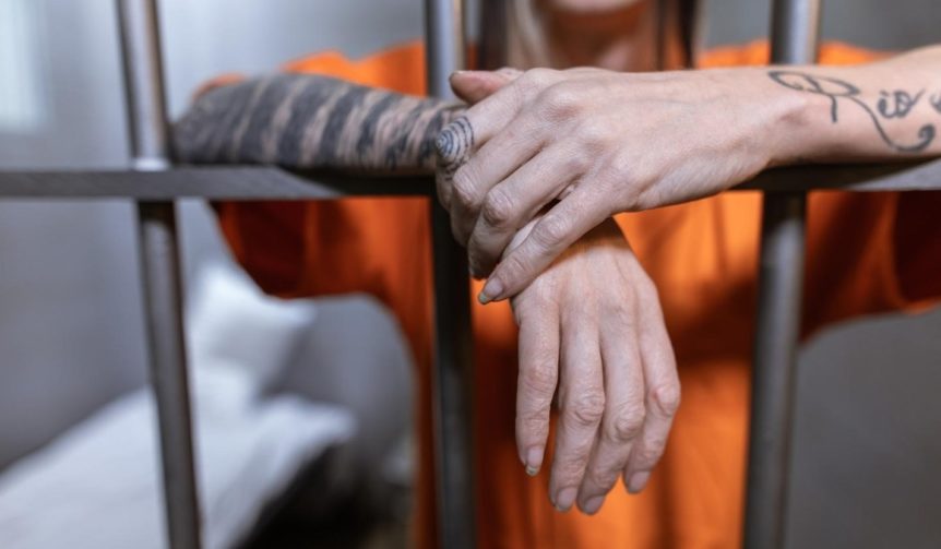Man in an orange jumpsuit behind bars