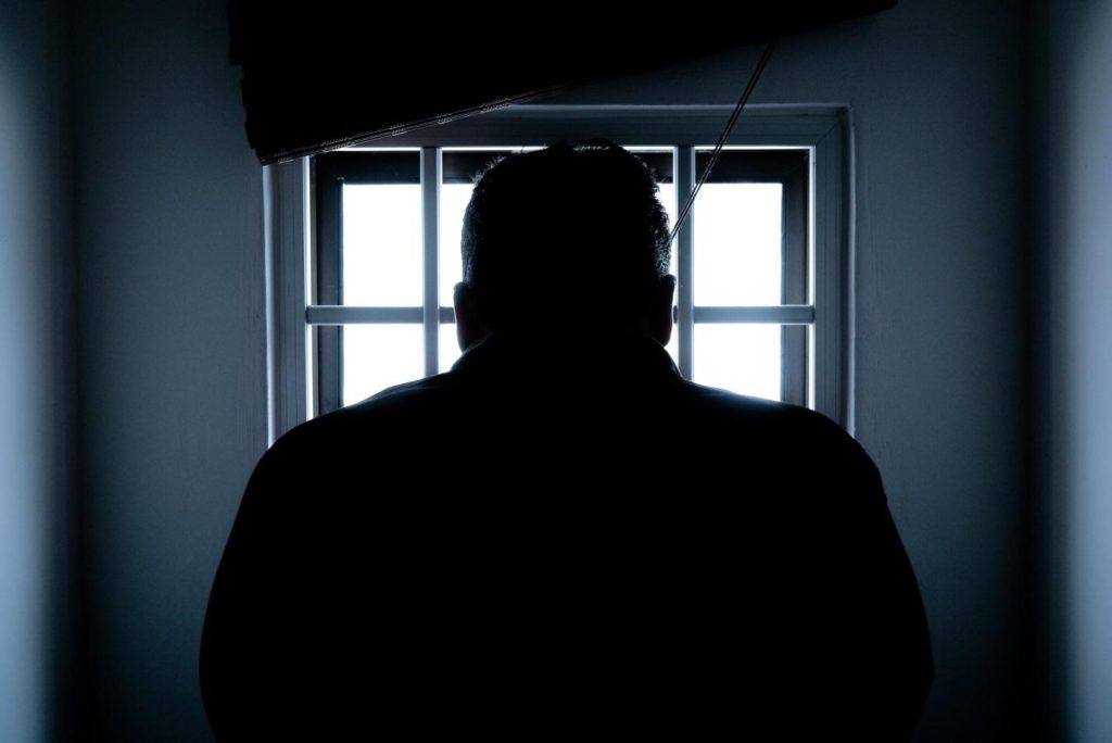 Silhouette of a man facing jail cell window