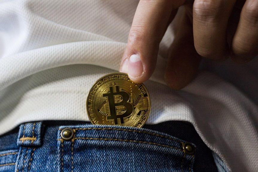 person slipping Bitcoin into their pocket
